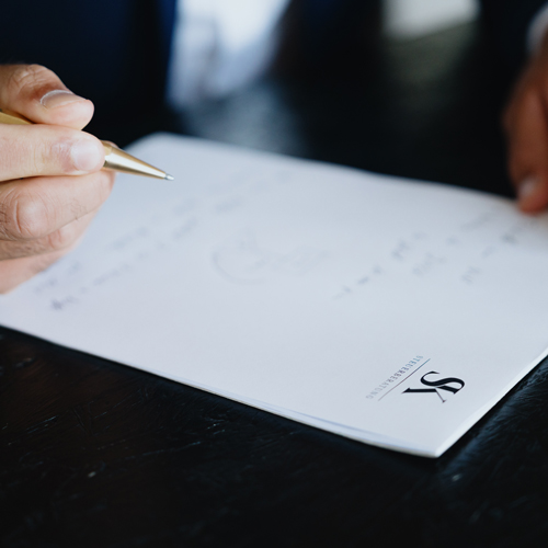 Foto von Steuerberater Kößler der etwas auf einen Block mit seinem Logo notiert